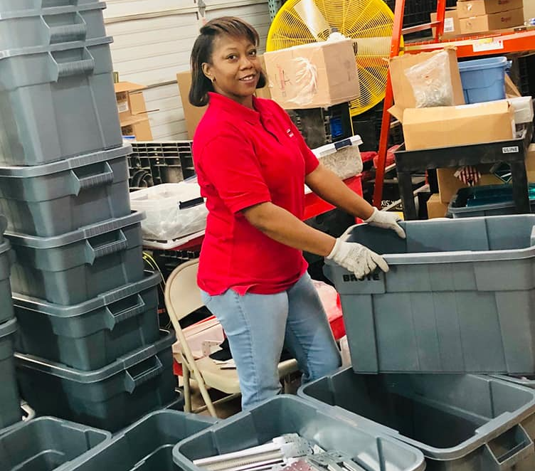 A woman in a red shirt is working in a warehouse