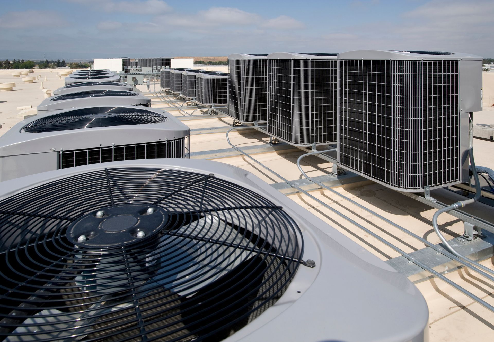 Several air conditioning condensers on the roof of a large commercial building. Several air conditioning condensers on the roof of a large commercial building.