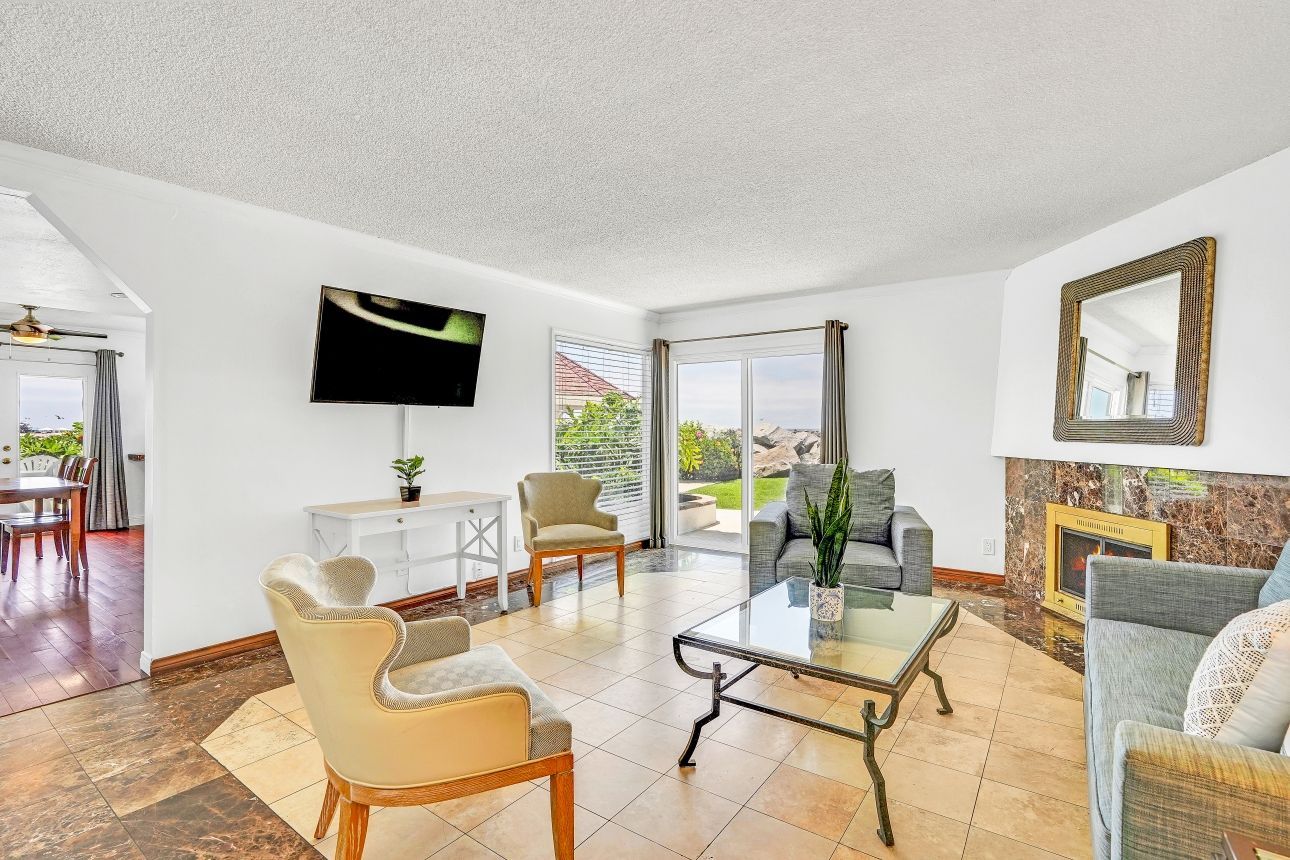 Living room with white walls, fireplace, TV, and a view of the backyard through a sliding glass door.