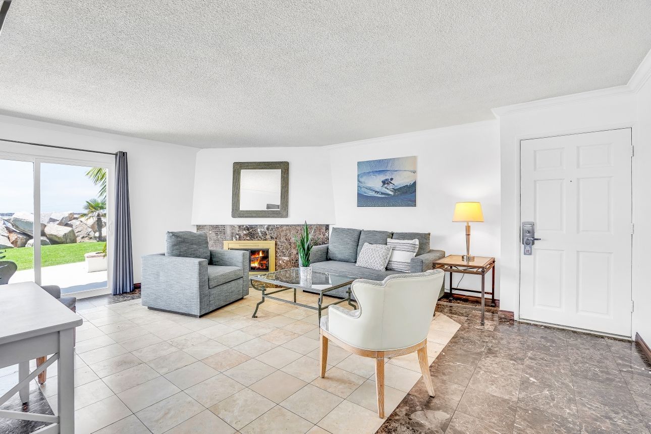 Living room with a fireplace, sofa, and outdoor view through sliding glass doors.