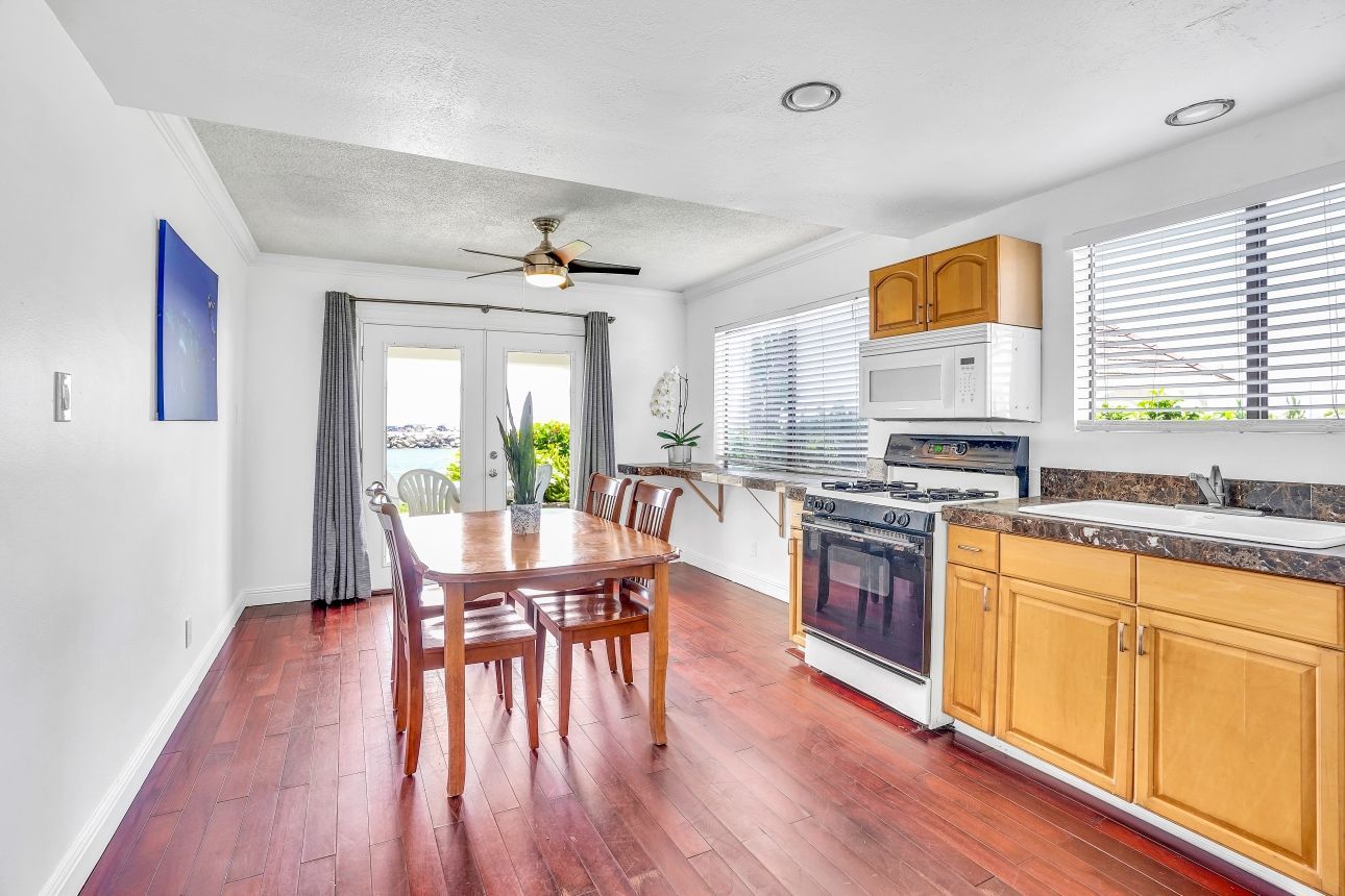 Kitchen with wood floors, dining table, stove, and windows. Bright and airy with natural light.