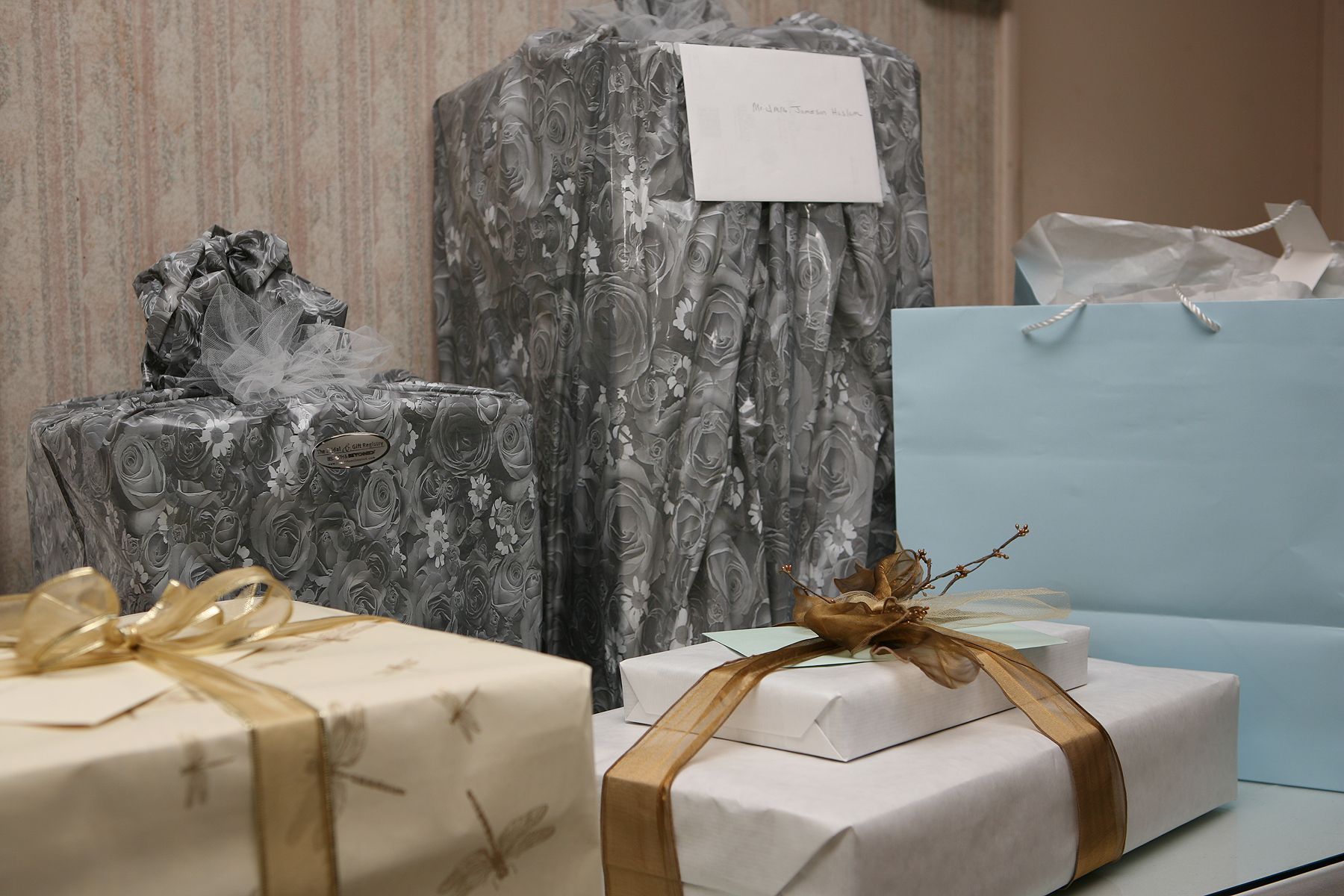 Gifts wrapped in various papers and ribbons, including gold and blue, sitting on a white surface.