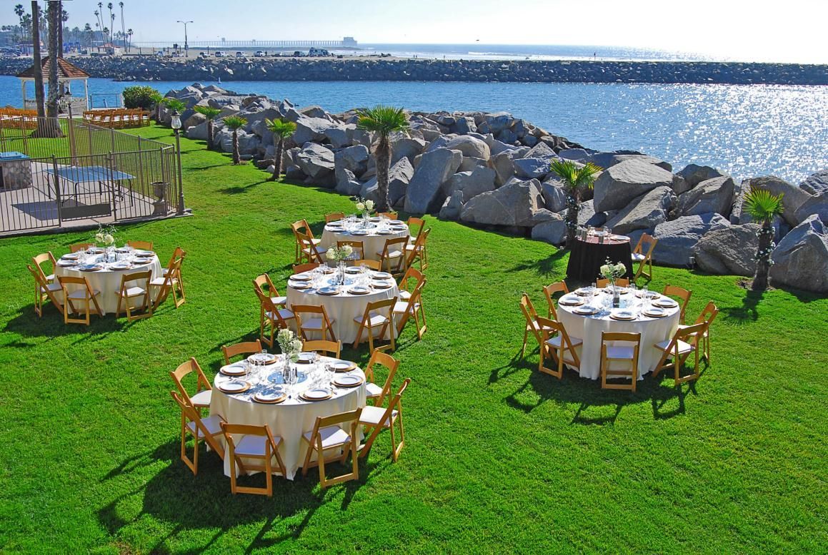 Outdoor event with round tables set on green grass overlooking the ocean.