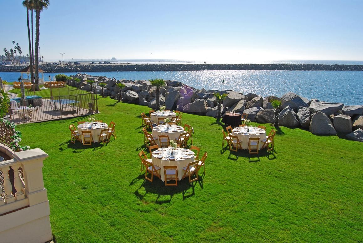 Round tables set on a green lawn overlooking the ocean.