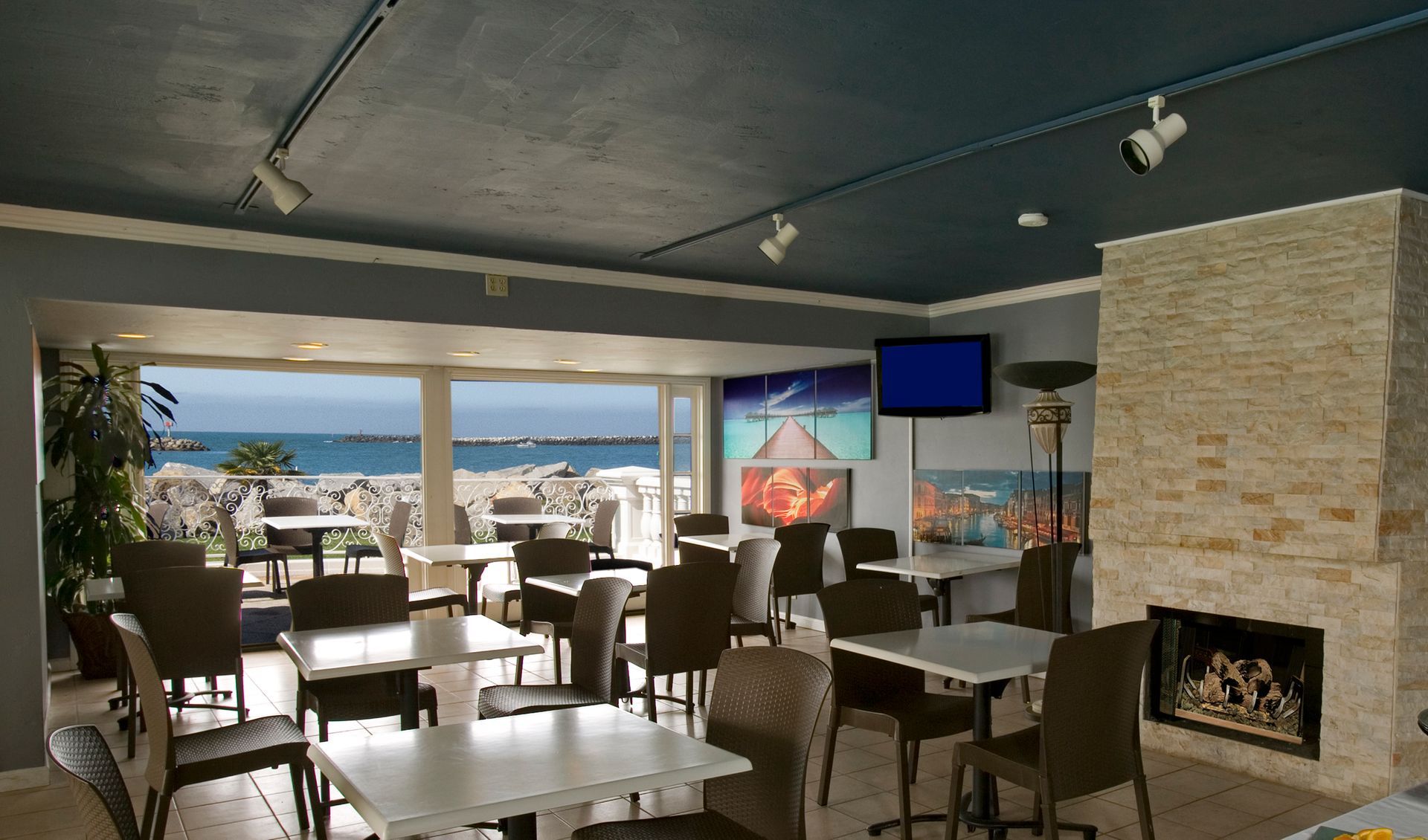 Restaurant interior with waterfront view, tables, chairs, fireplace, art, and television.