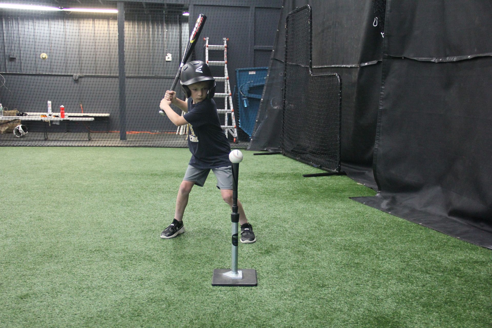 A young boy is swinging a baseball bat at a tee.