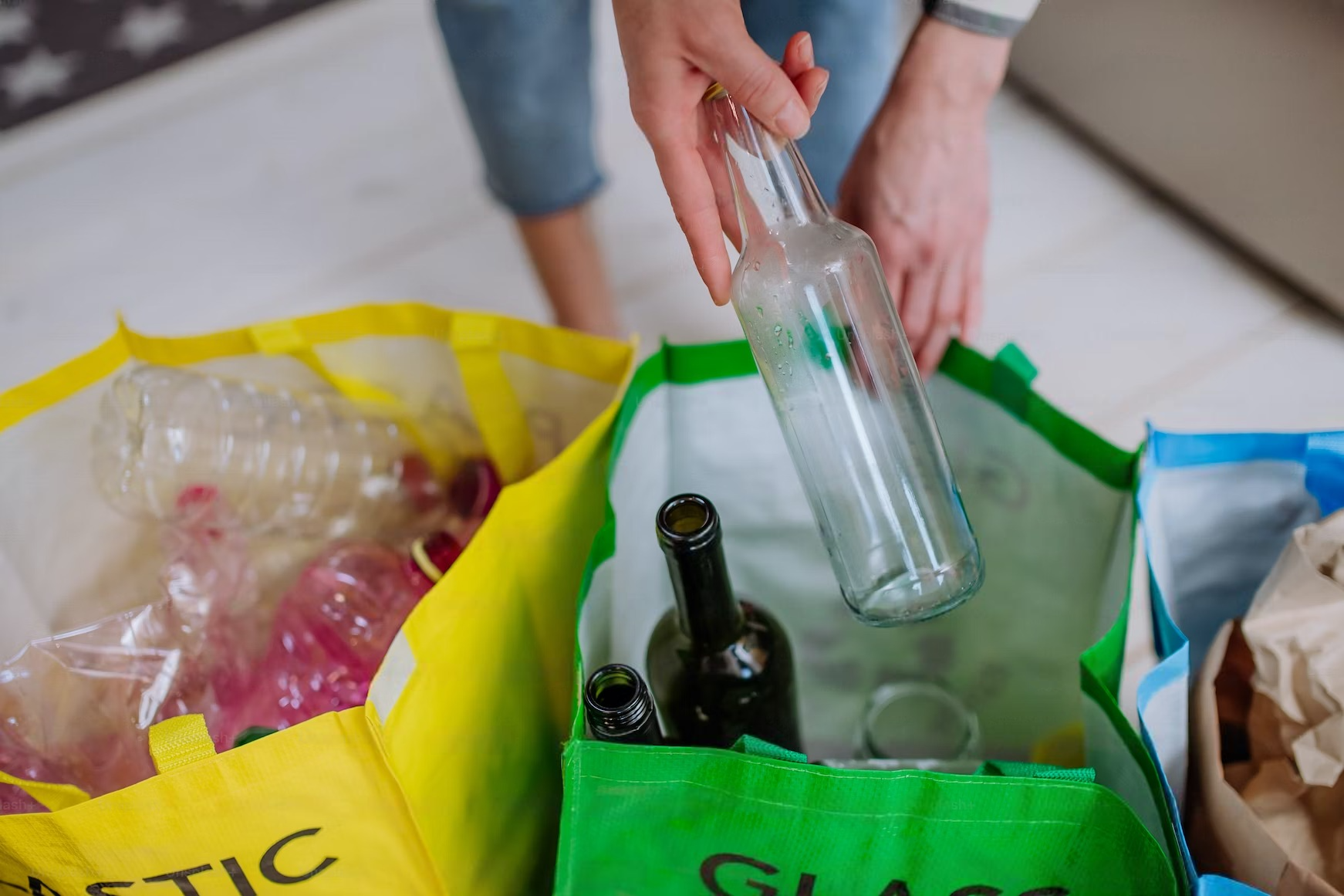 a person is putting a glass bottle into a recycling bag .