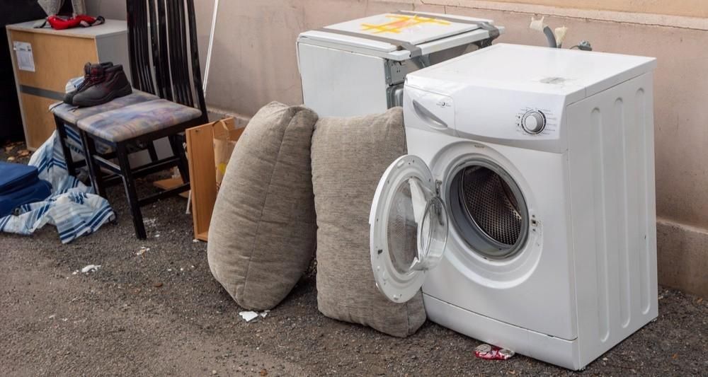 a washing machine is sitting on the ground next to a chair .