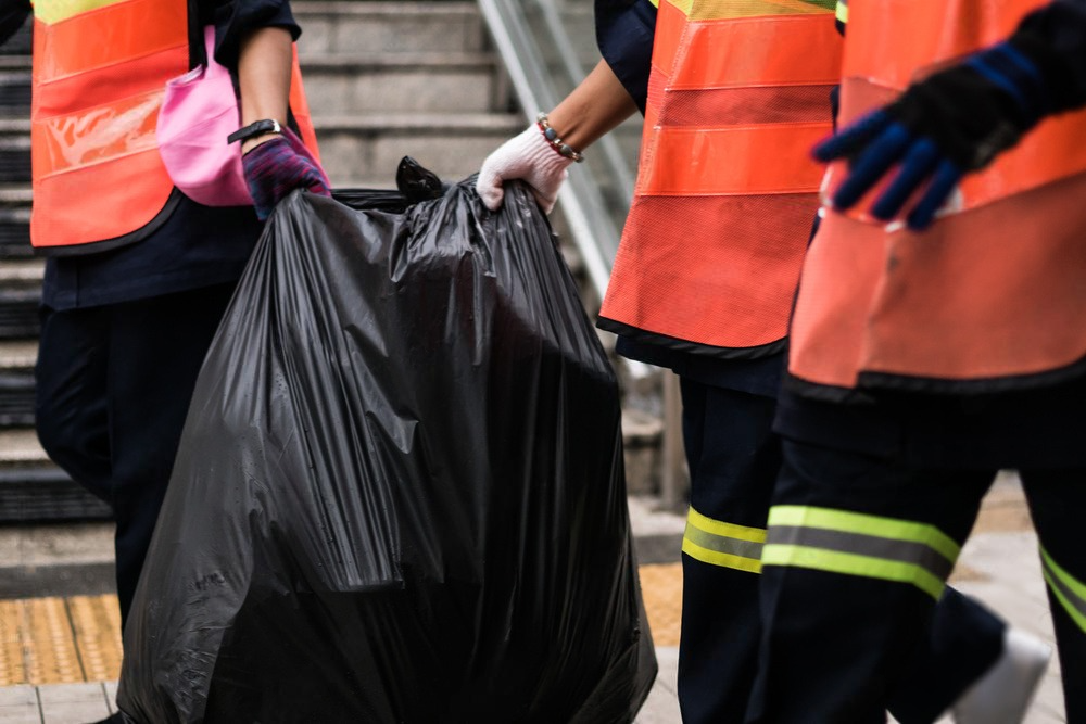 a person is throwing a trash bag into a trash can .