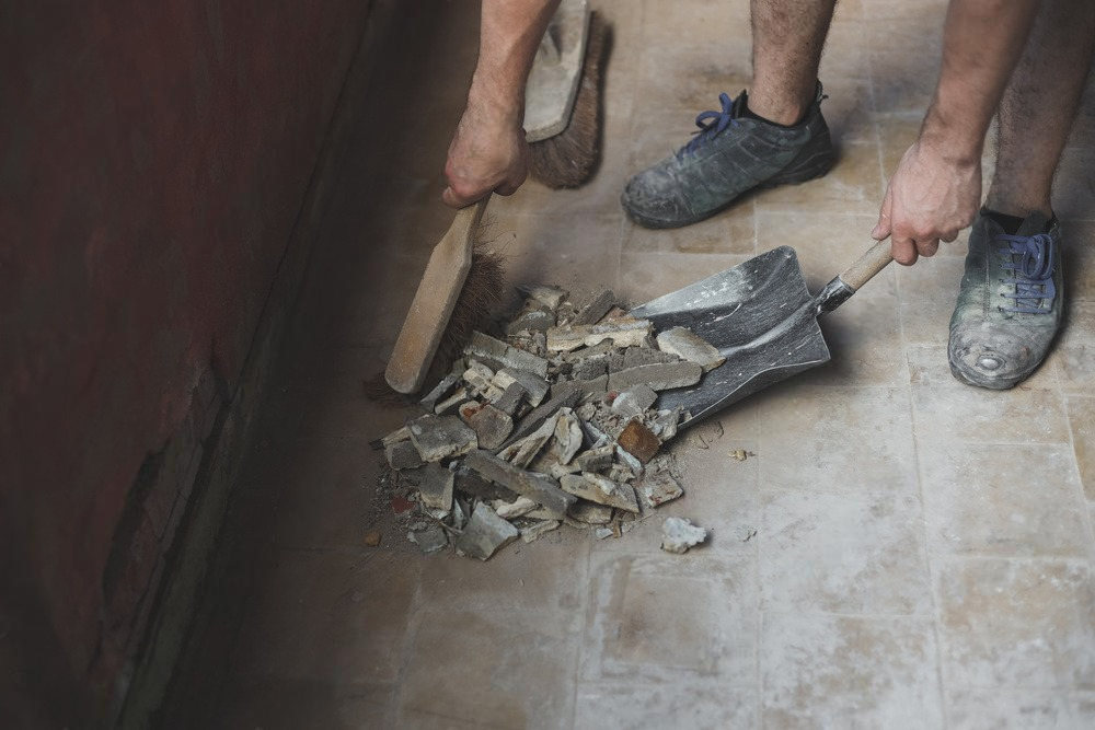 a man is cleaning the floor with a shovel and brush .