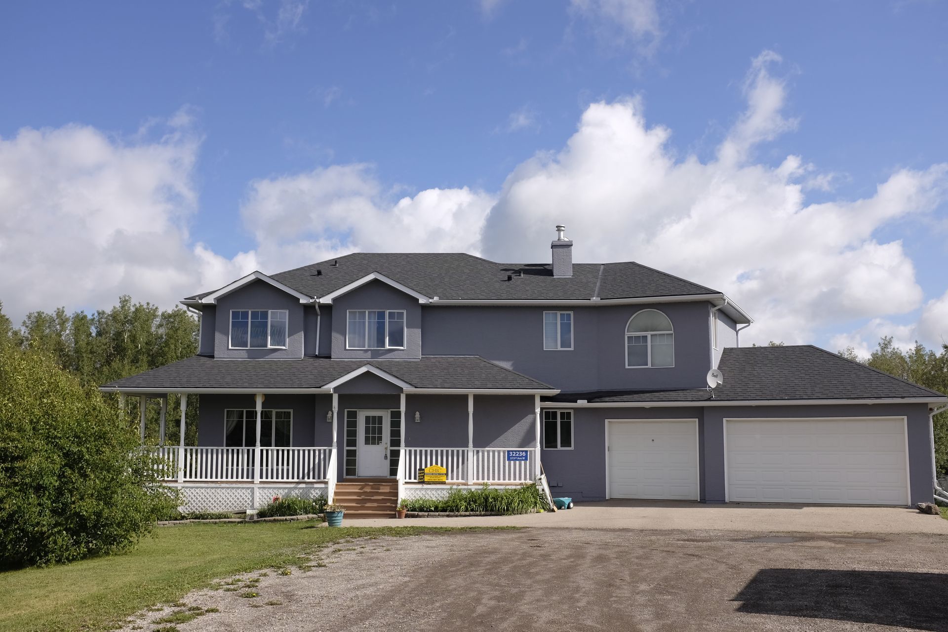 A large house with a gray roof and white garage doors