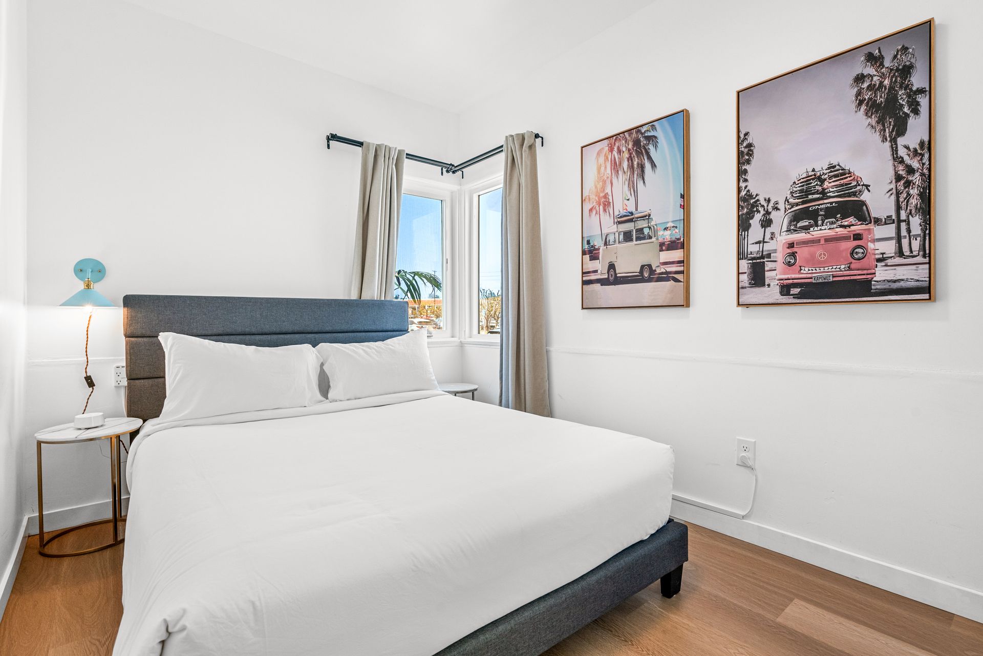 A bedroom with a king size bed and two paintings on the wall.