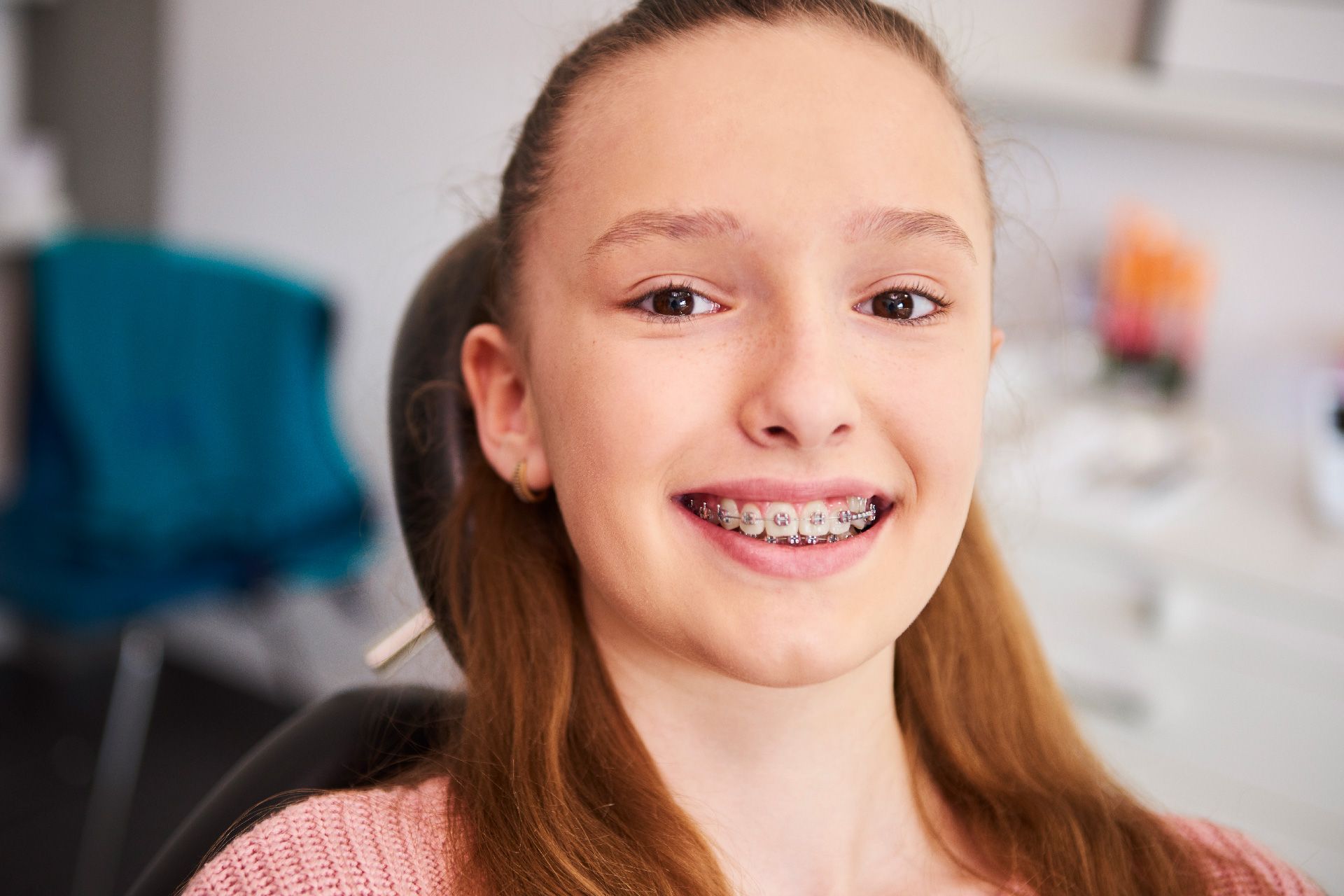 Niña con brackets sonriendo en el sillón del dentista.