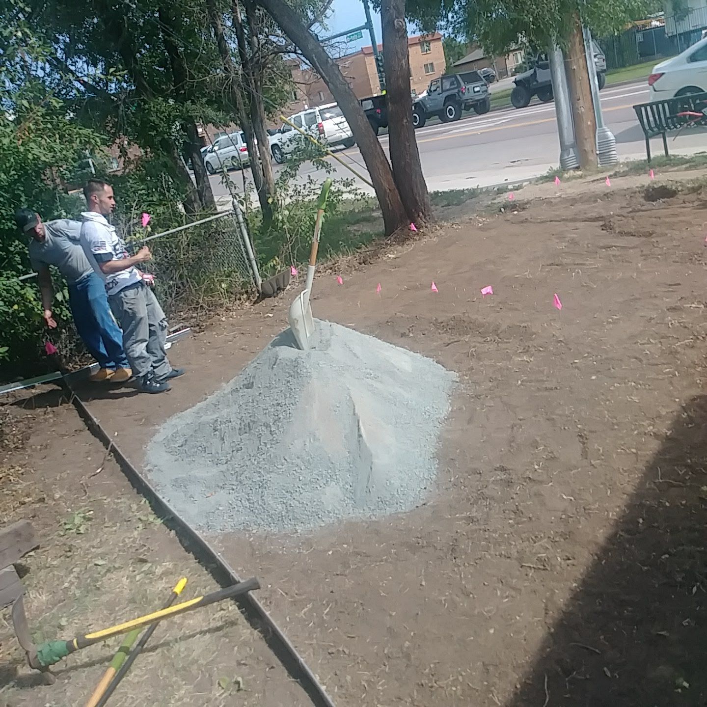 A group of people are standing around a pile of dirt.