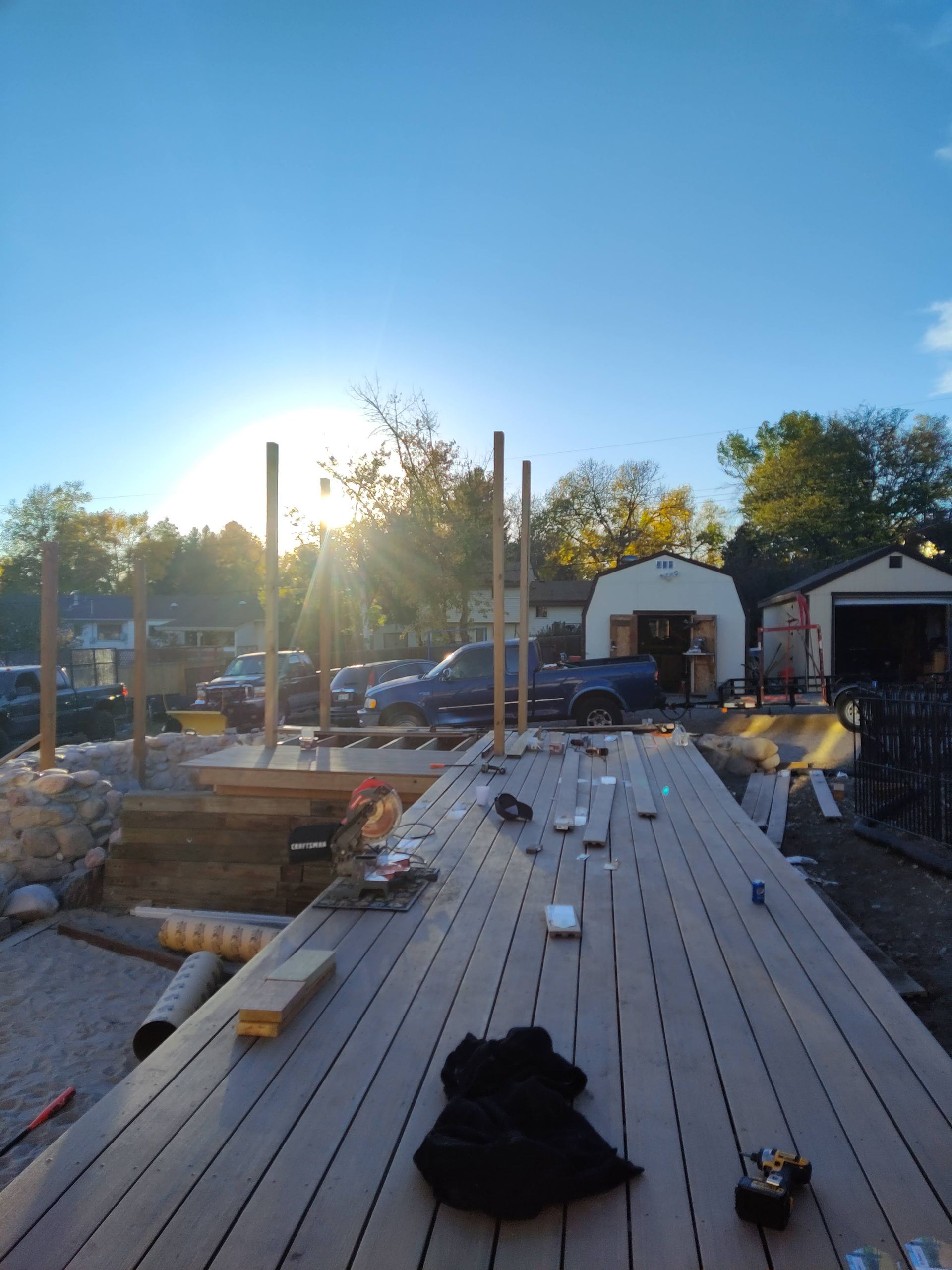 The sun is shining through the trees behind a wooden deck