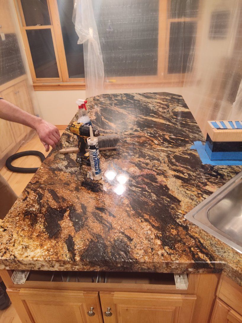 A person is polishing a granite counter top in a kitchen.
