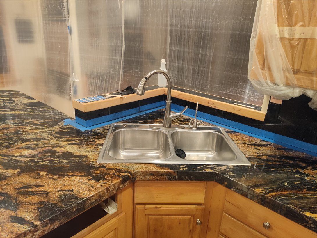 A kitchen sink is sitting on top of a granite counter top.
