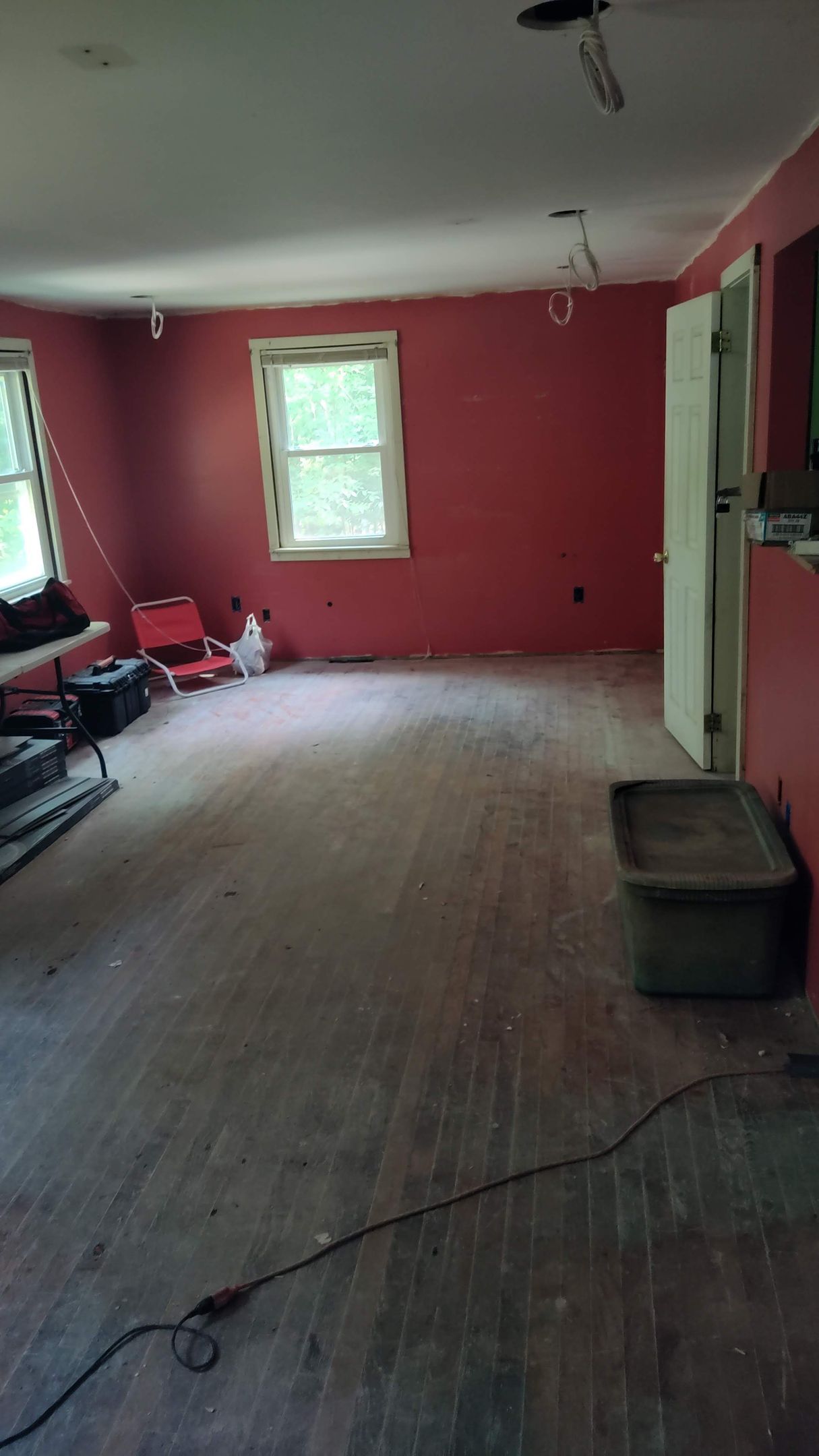 An empty room with red walls and wooden floors.
