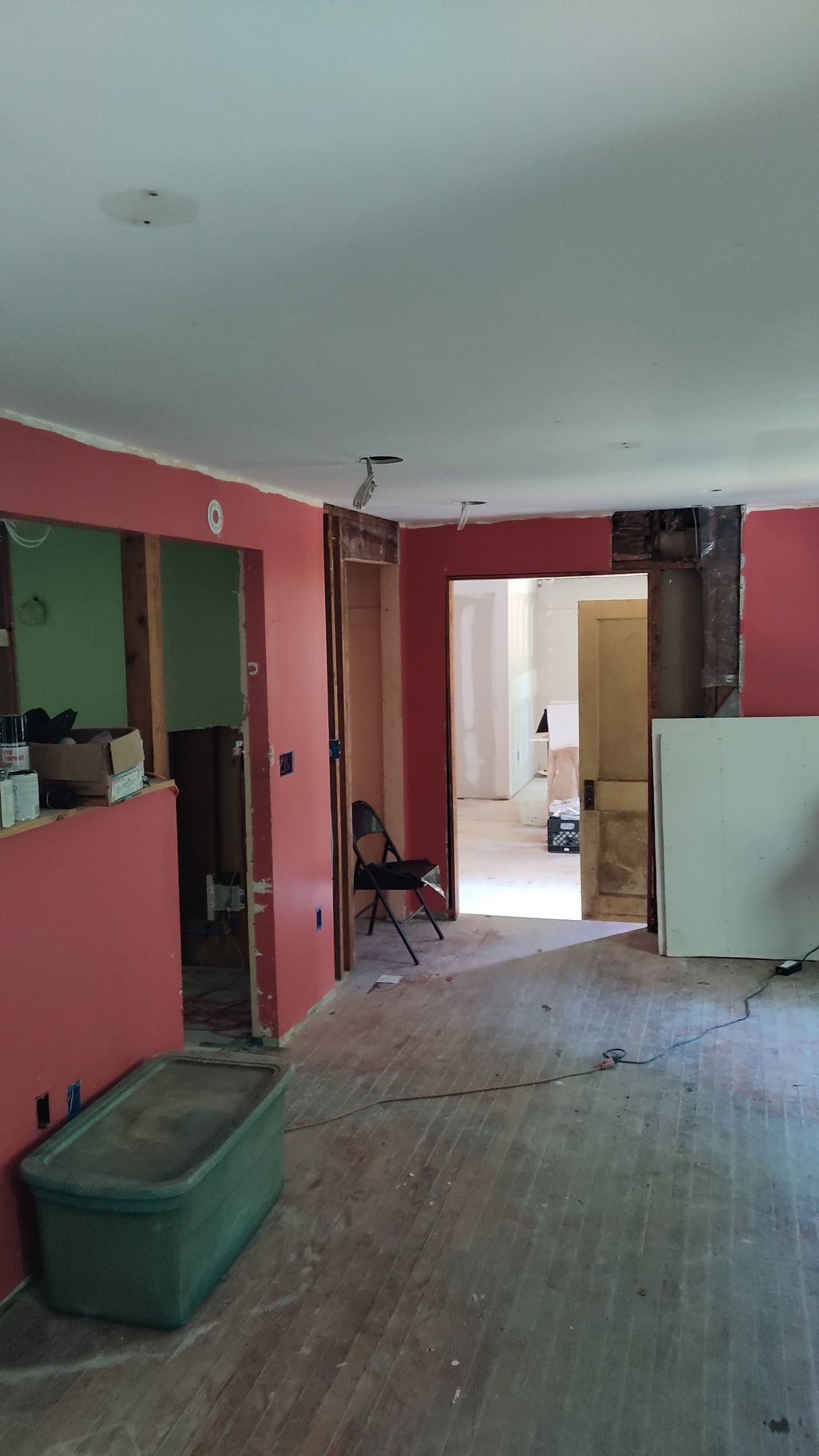 A living room with red walls and a green bin on the floor.