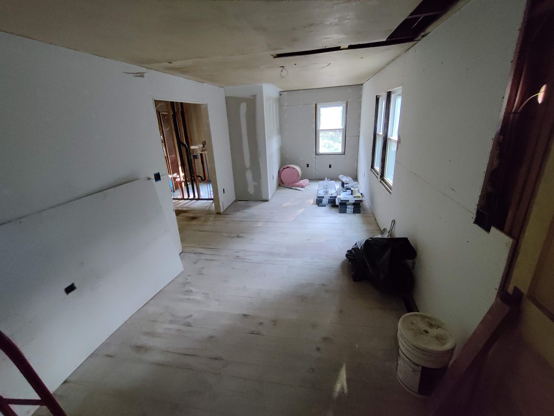 A room with white walls and wooden floors is being remodeled.