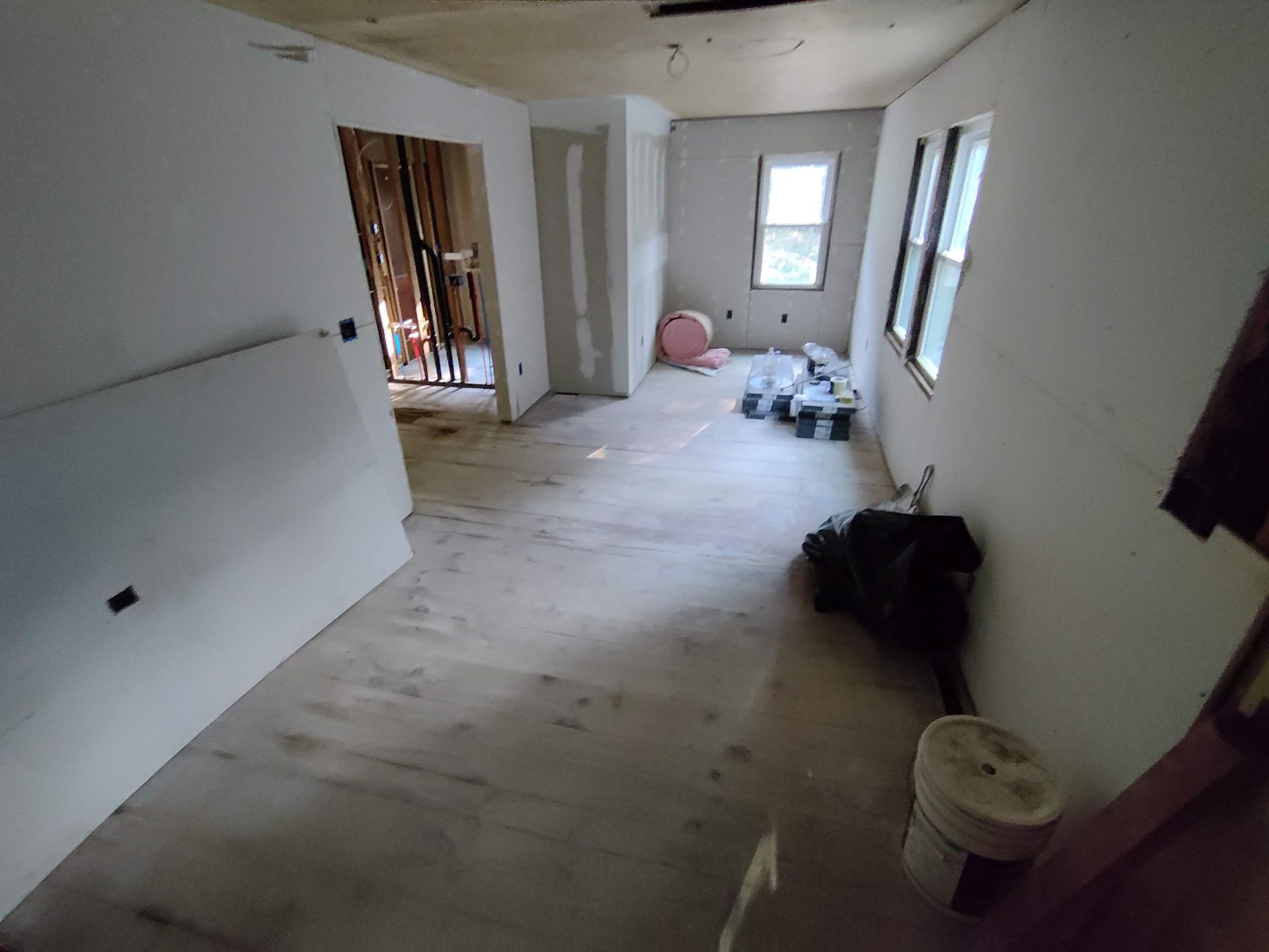 A room under construction with a bucket of paint on the floor.