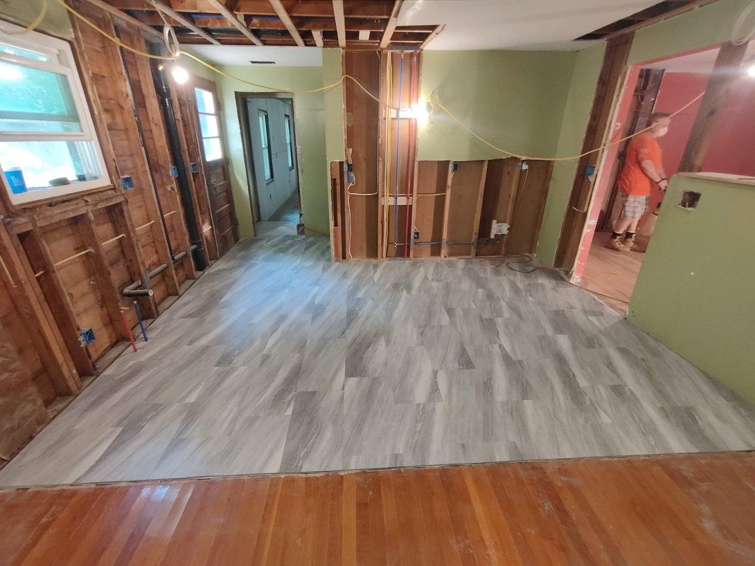 A room with a wooden floor and a man standing in the doorway.