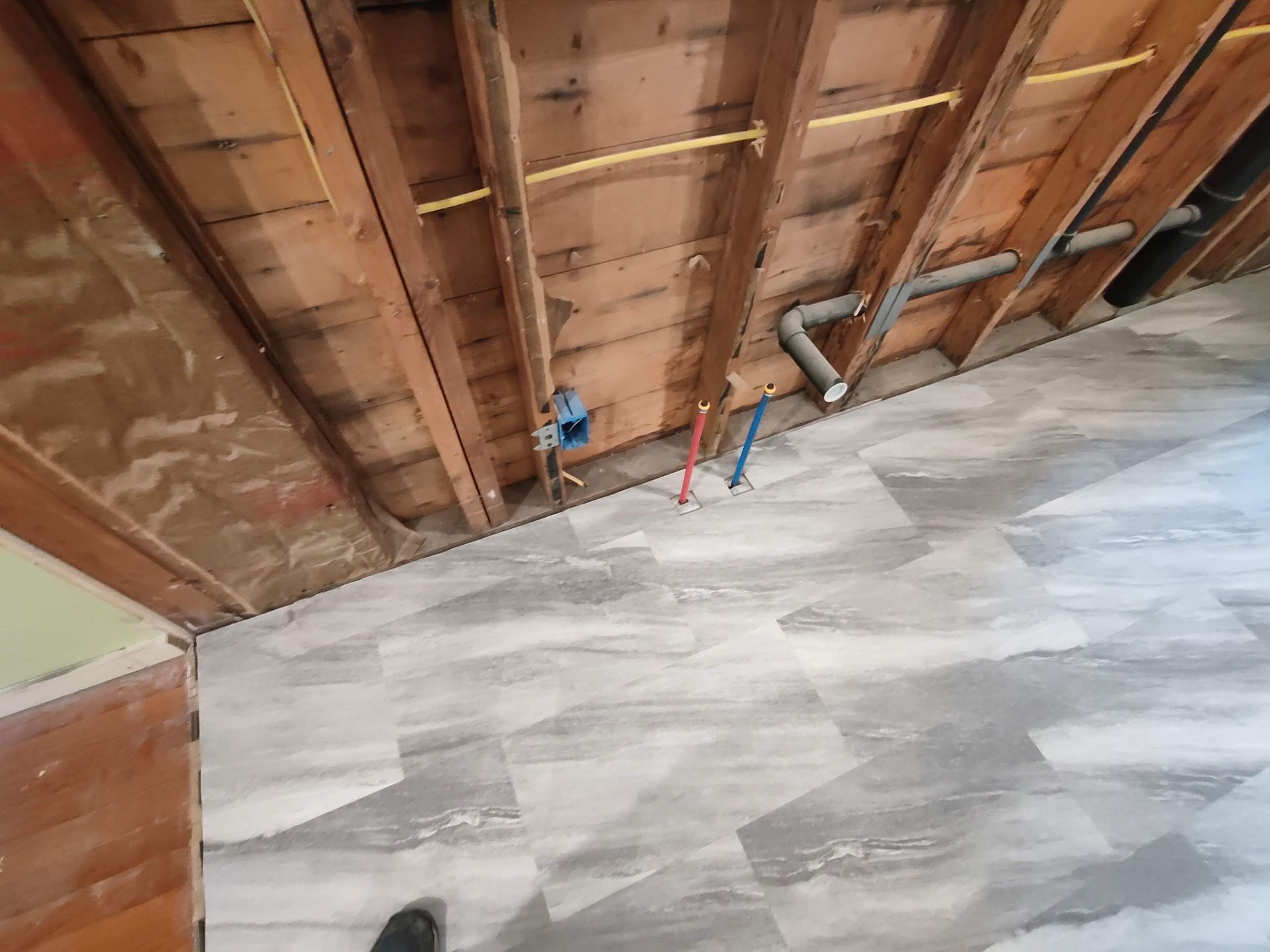 A person is standing in a room with a wooden wall and a tiled floor.