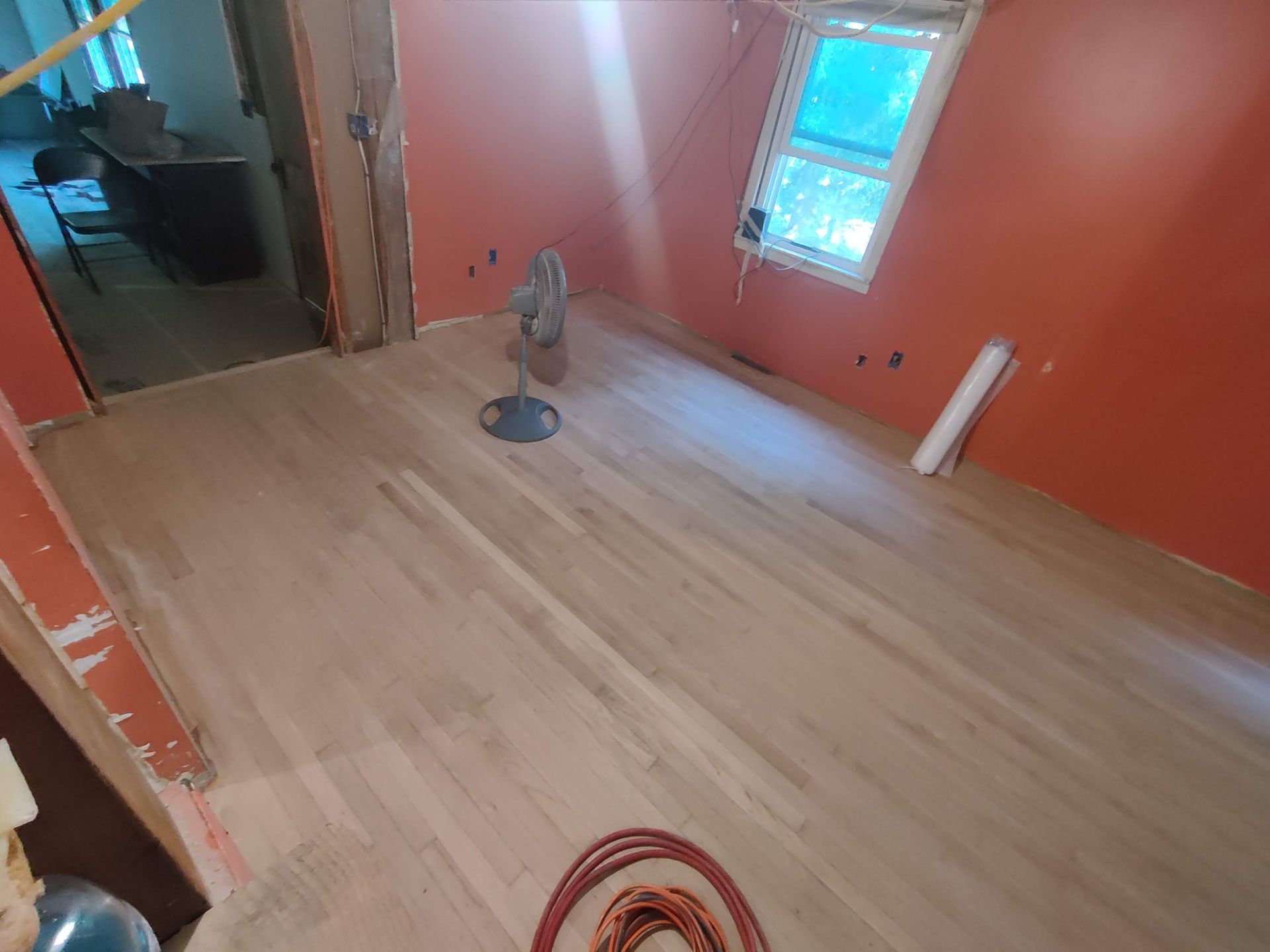 A room with a wooden floor and a fan in it.