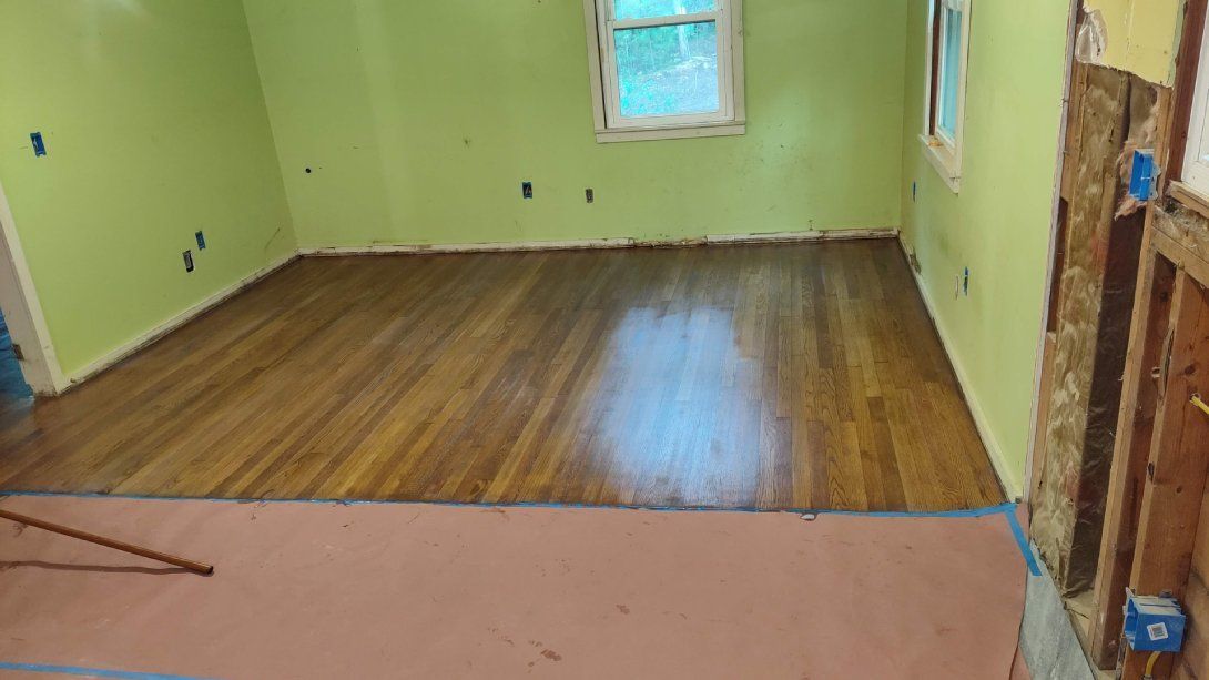 A room with hardwood floors and green walls is being remodeled.