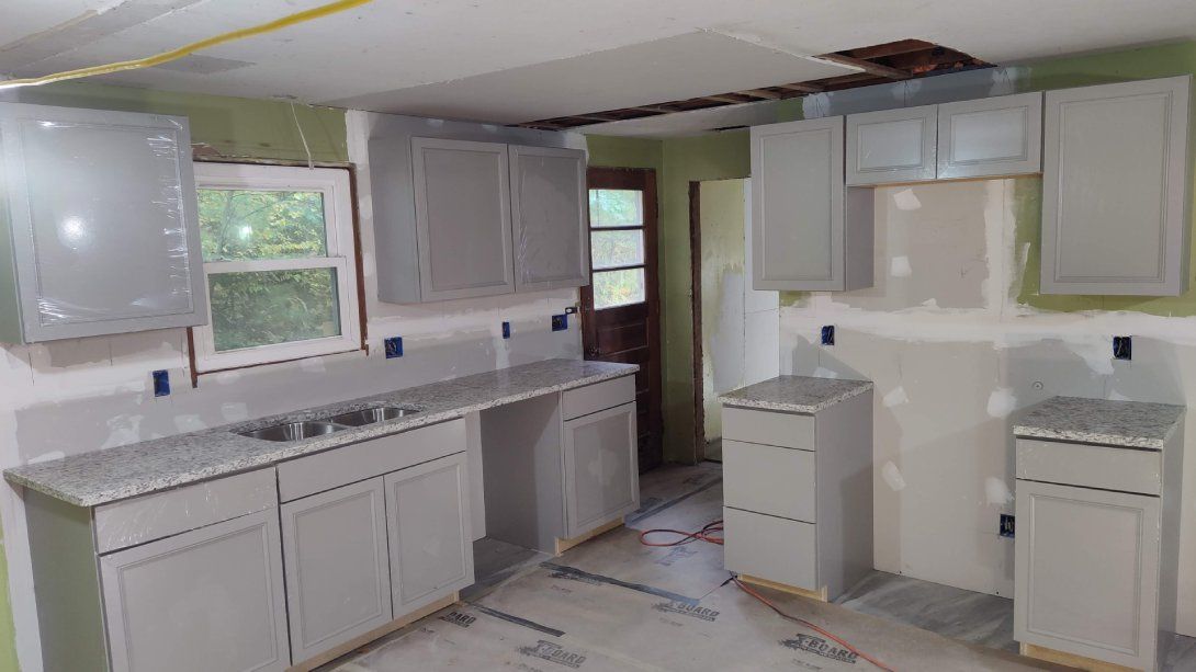 A kitchen under construction with white cabinets and granite counter tops.