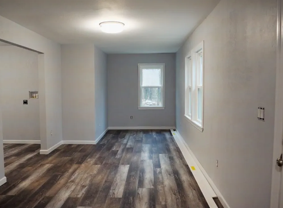 An empty room with hardwood floors and a window.