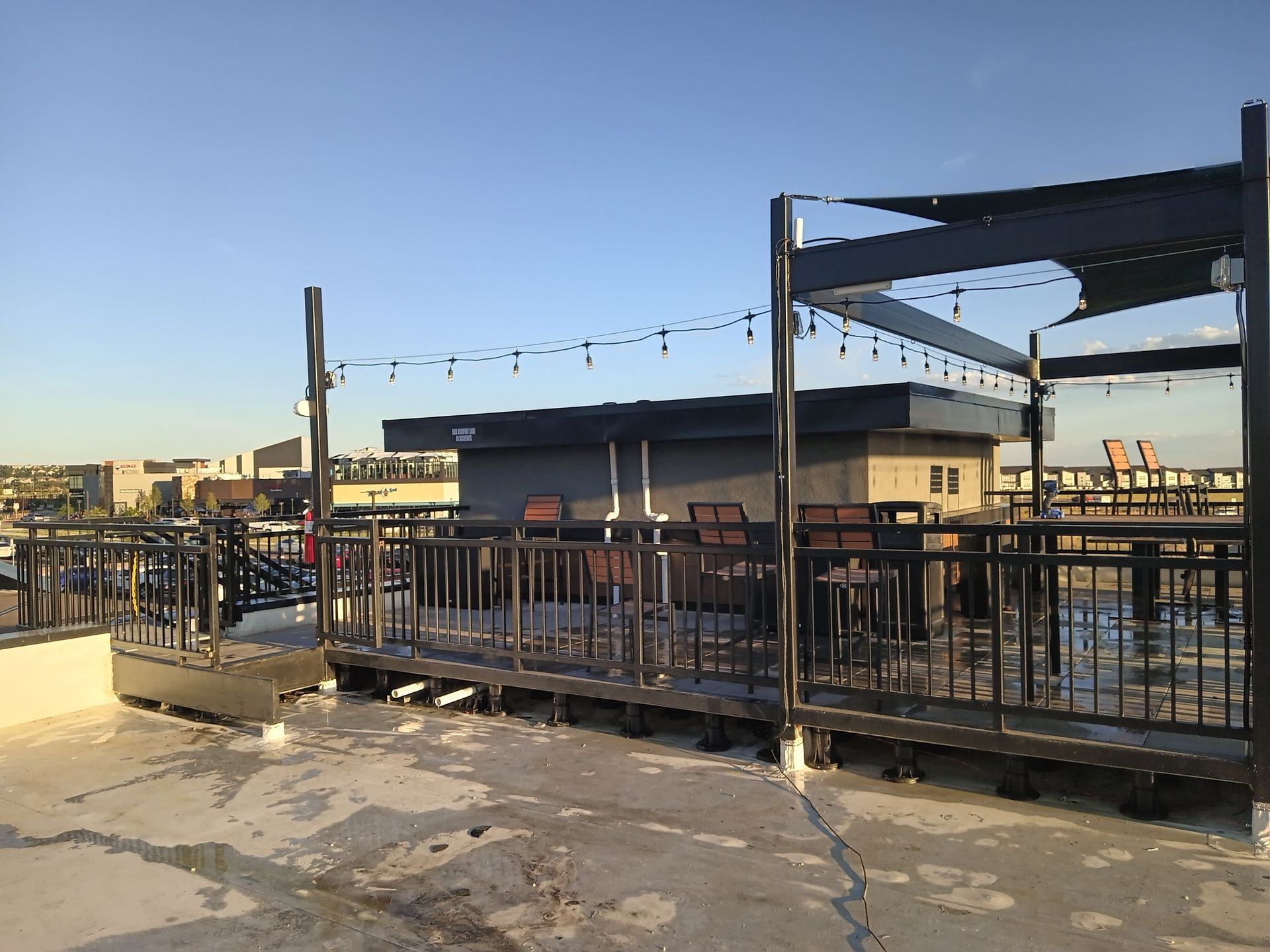 A rooftop deck with tables and chairs and a canopy