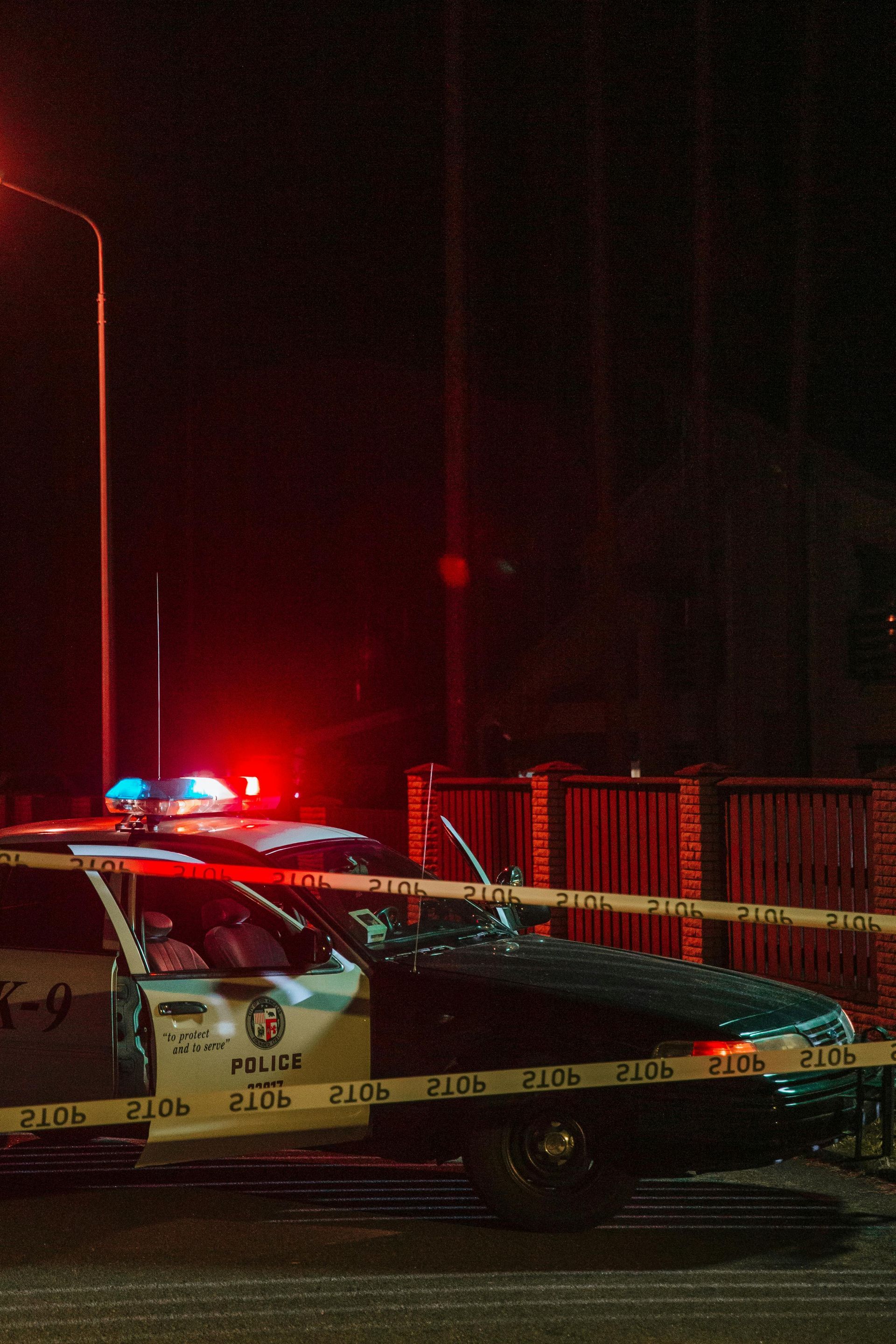A police car is parked on the side of the road at night.