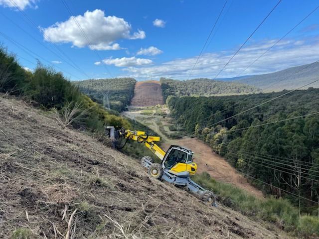 A bulldozer is driving down a dirt road with mountains in the background.