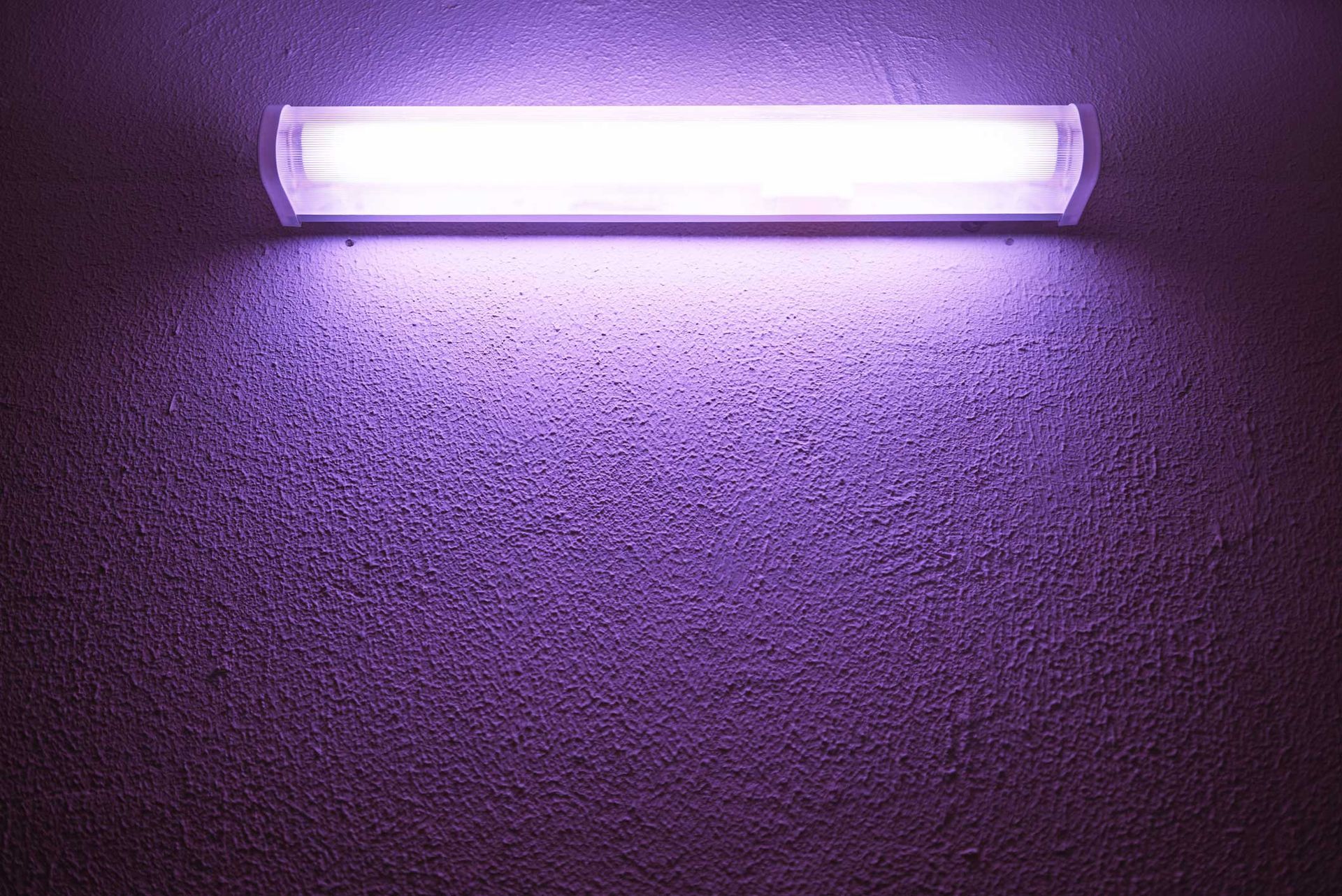 A purple light is shining on a purple wall.