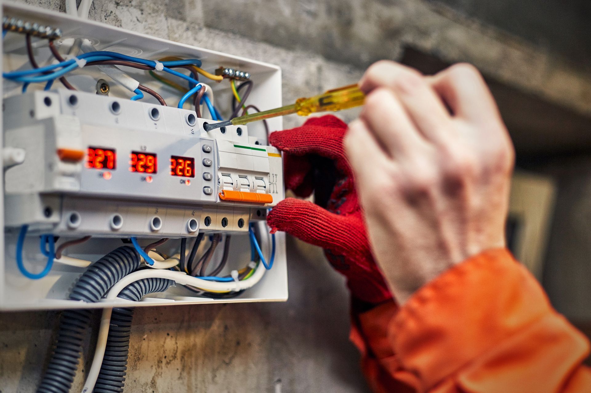A person is working on an electrical box with a screwdriver.