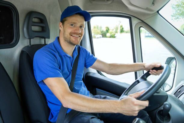 A delivery man is sitting in the driver's seat of a van.