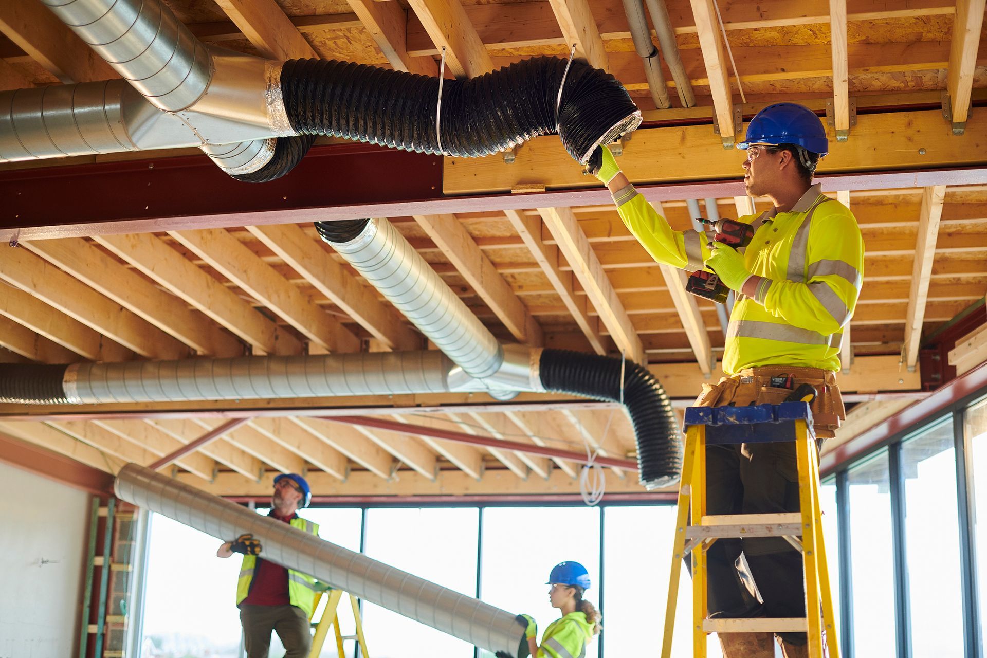 A group of construction workers are working on the ceiling of a building.