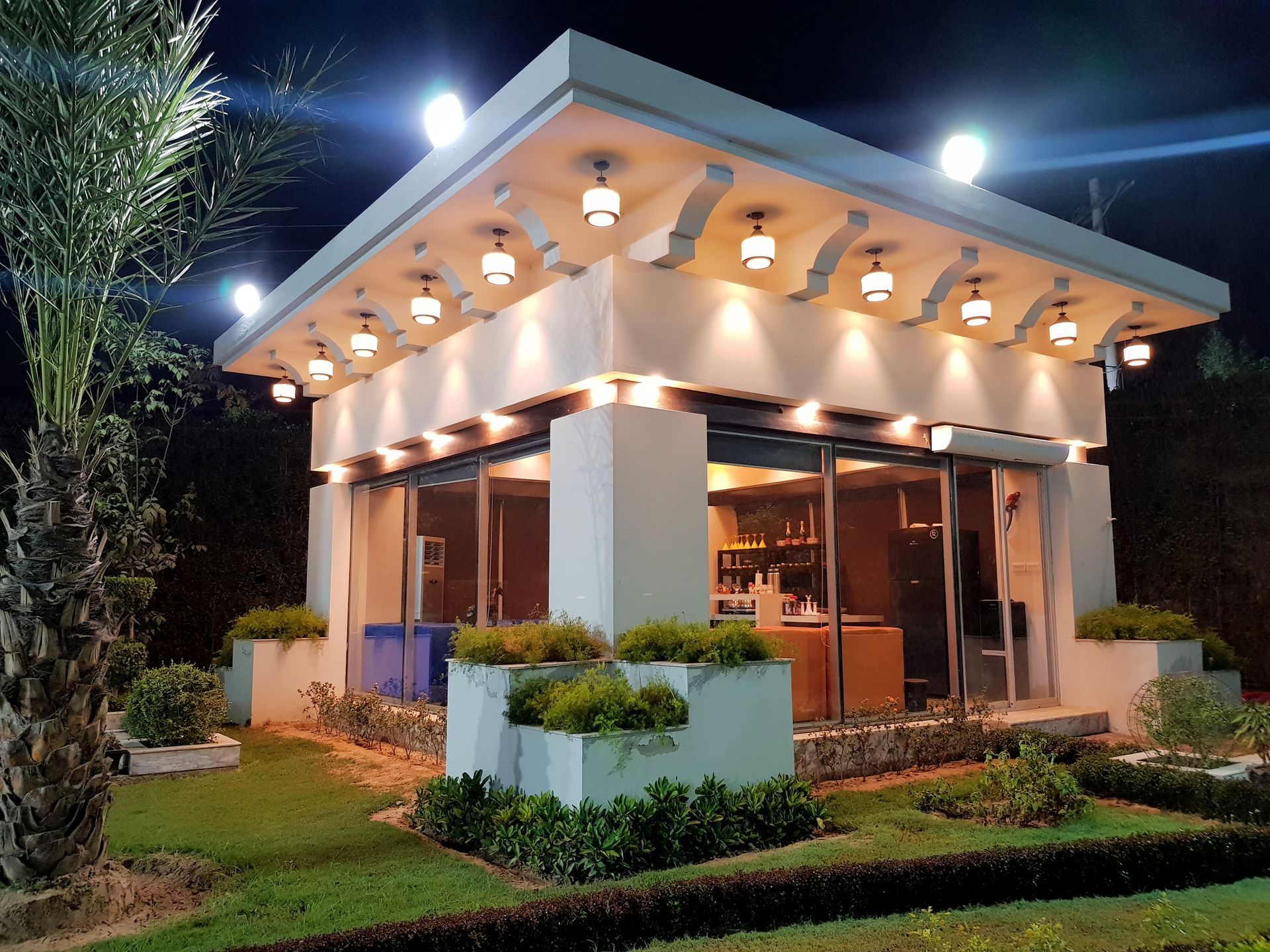 A small white house with a lot of windows is lit up at night.