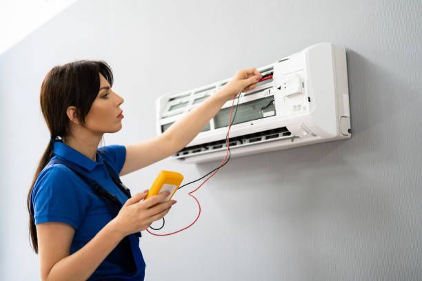 A woman is fixing an air conditioner with a multimeter.