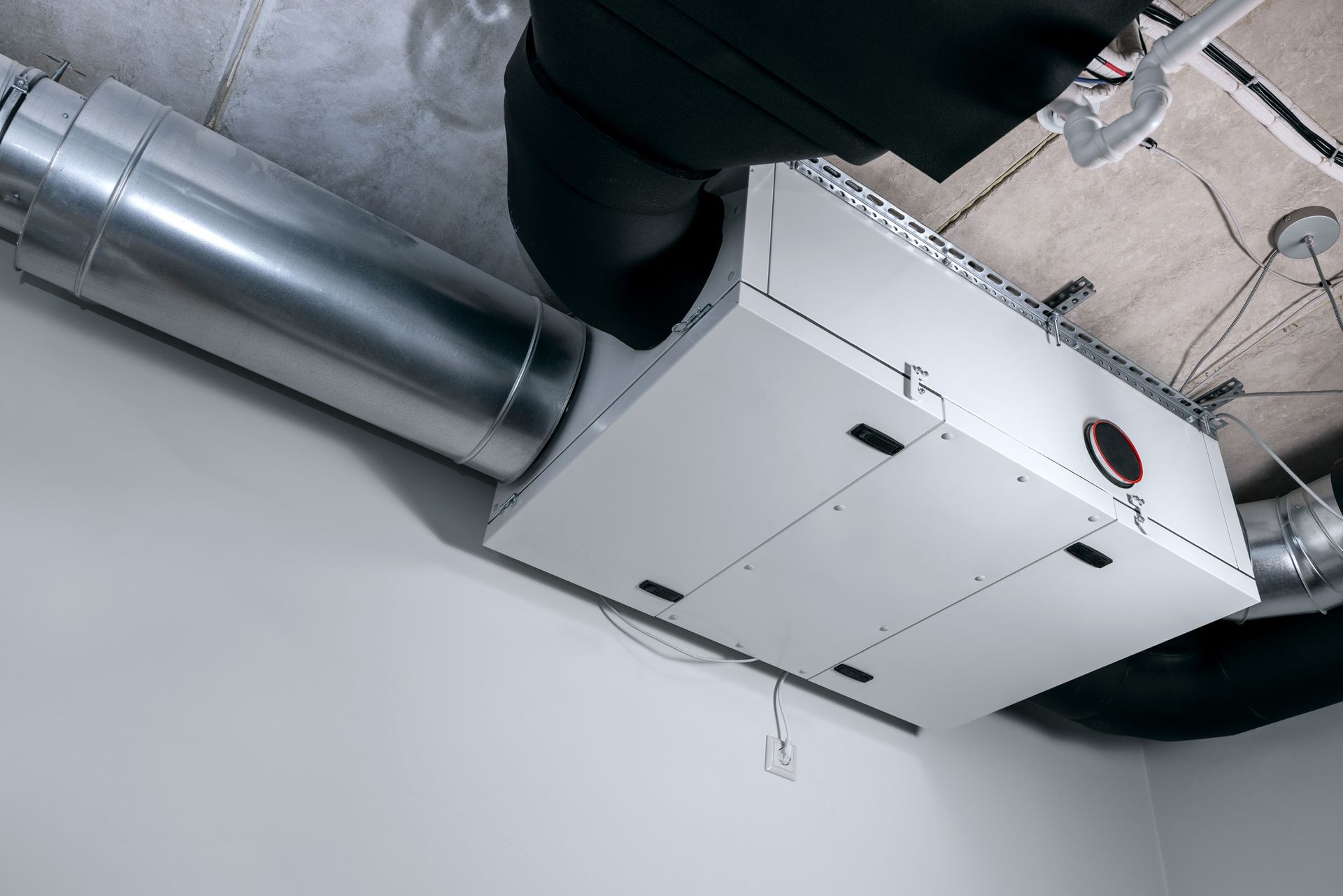 Modern heat recovery ventilation system mounted on ceiling in house service room.