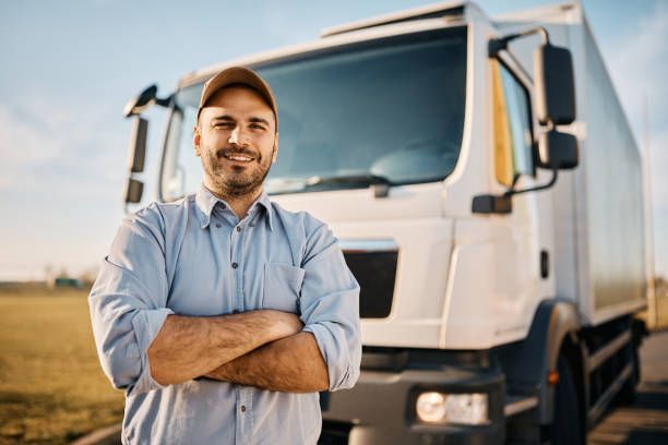 A man is standing in front of a truck with his arms crossed.