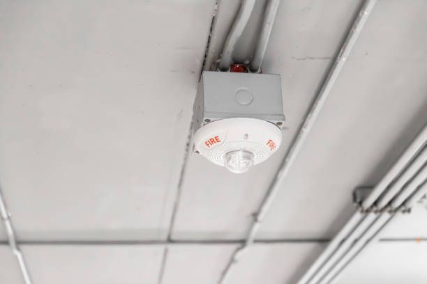 A fire alarm is hanging from the ceiling of a building.