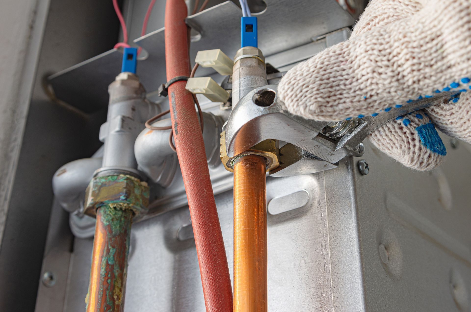 A person is working on a gas heater with a wrench.