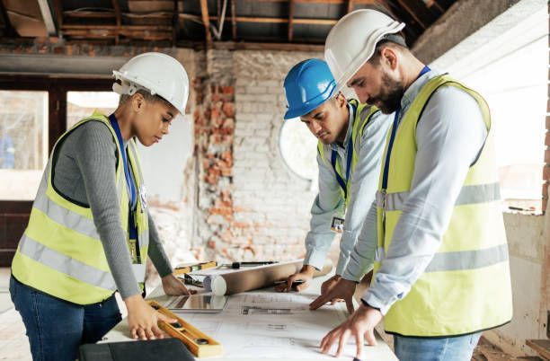 A group of construction workers are looking at a blueprint on a table.