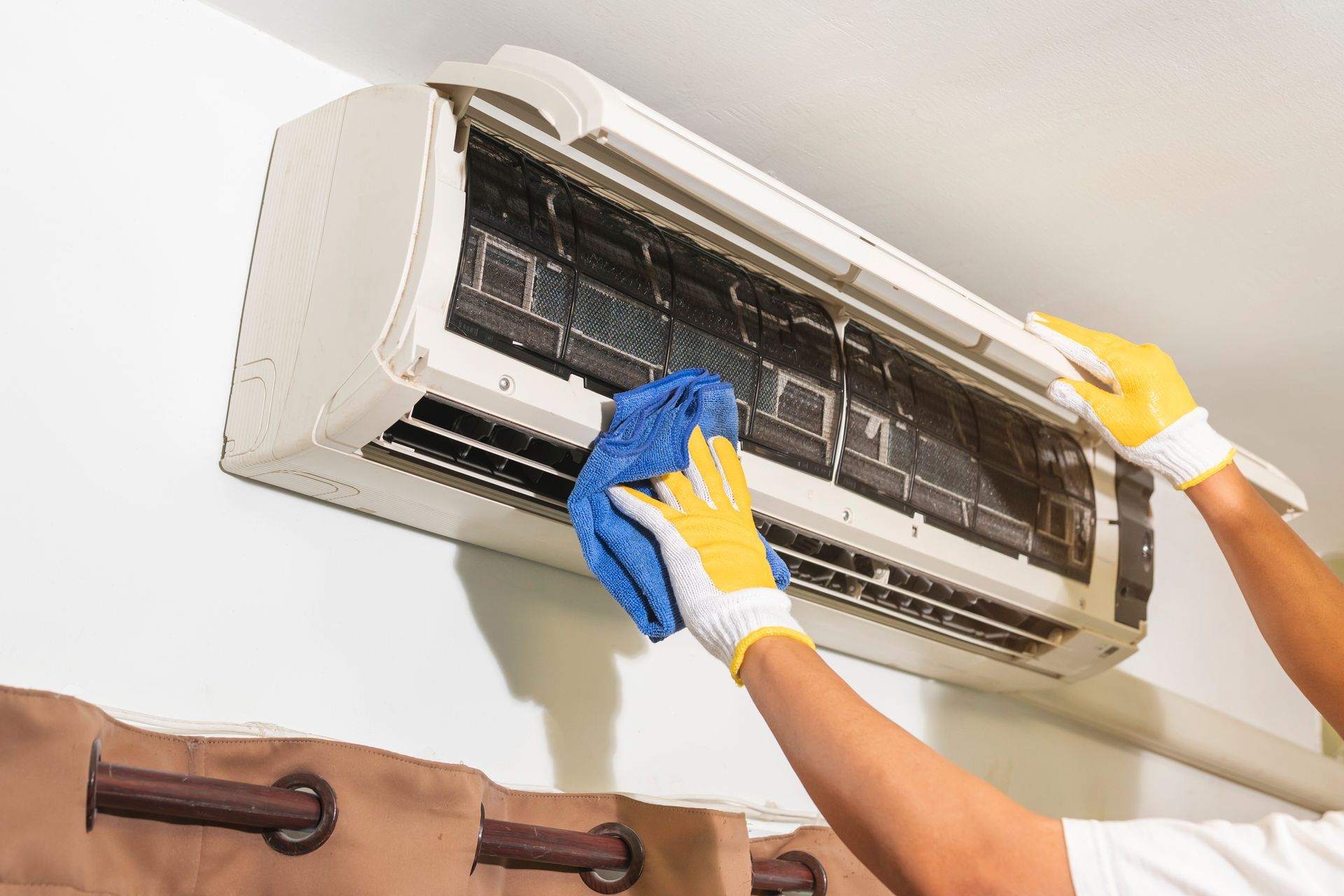 A person is cleaning an air conditioner with a cloth.