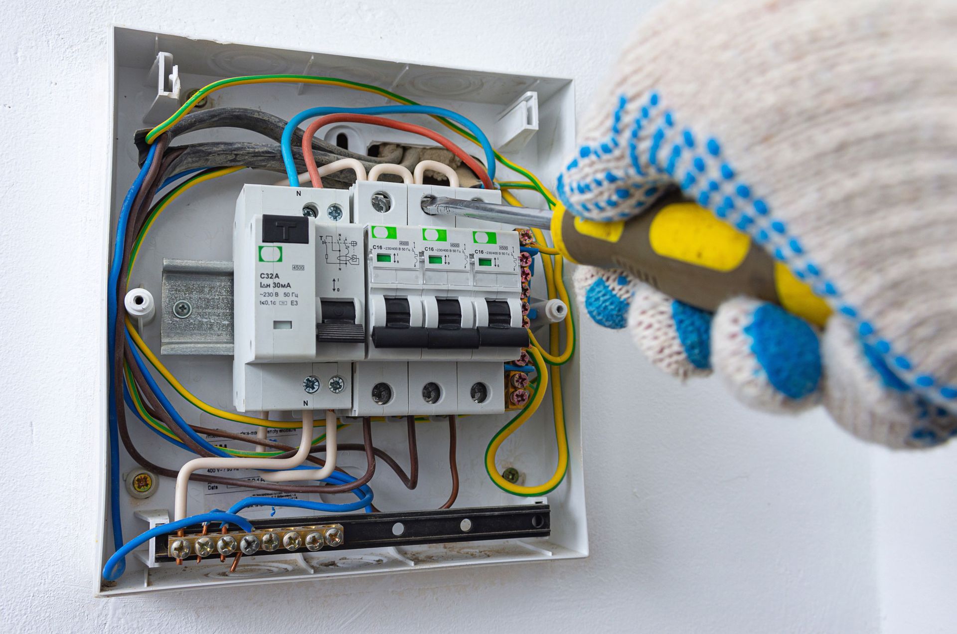 A person is working on an electrical box with a screwdriver.