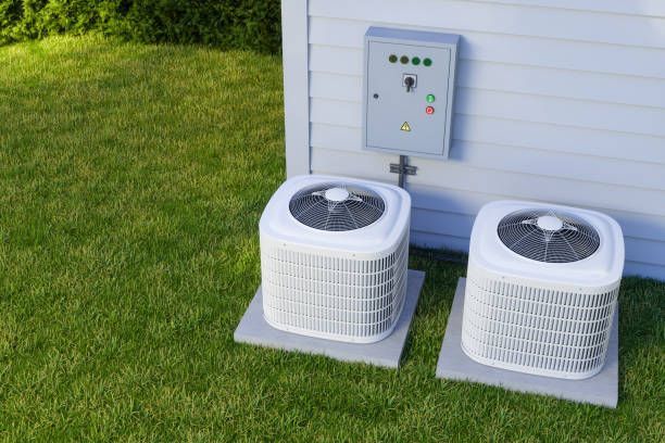 Two white air conditioners are sitting on the side of a house.