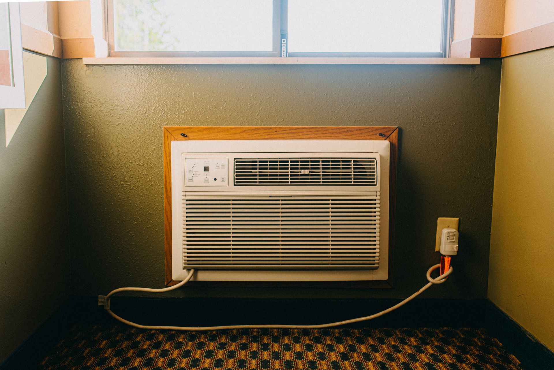 A room with a window and an air conditioner on the wall.