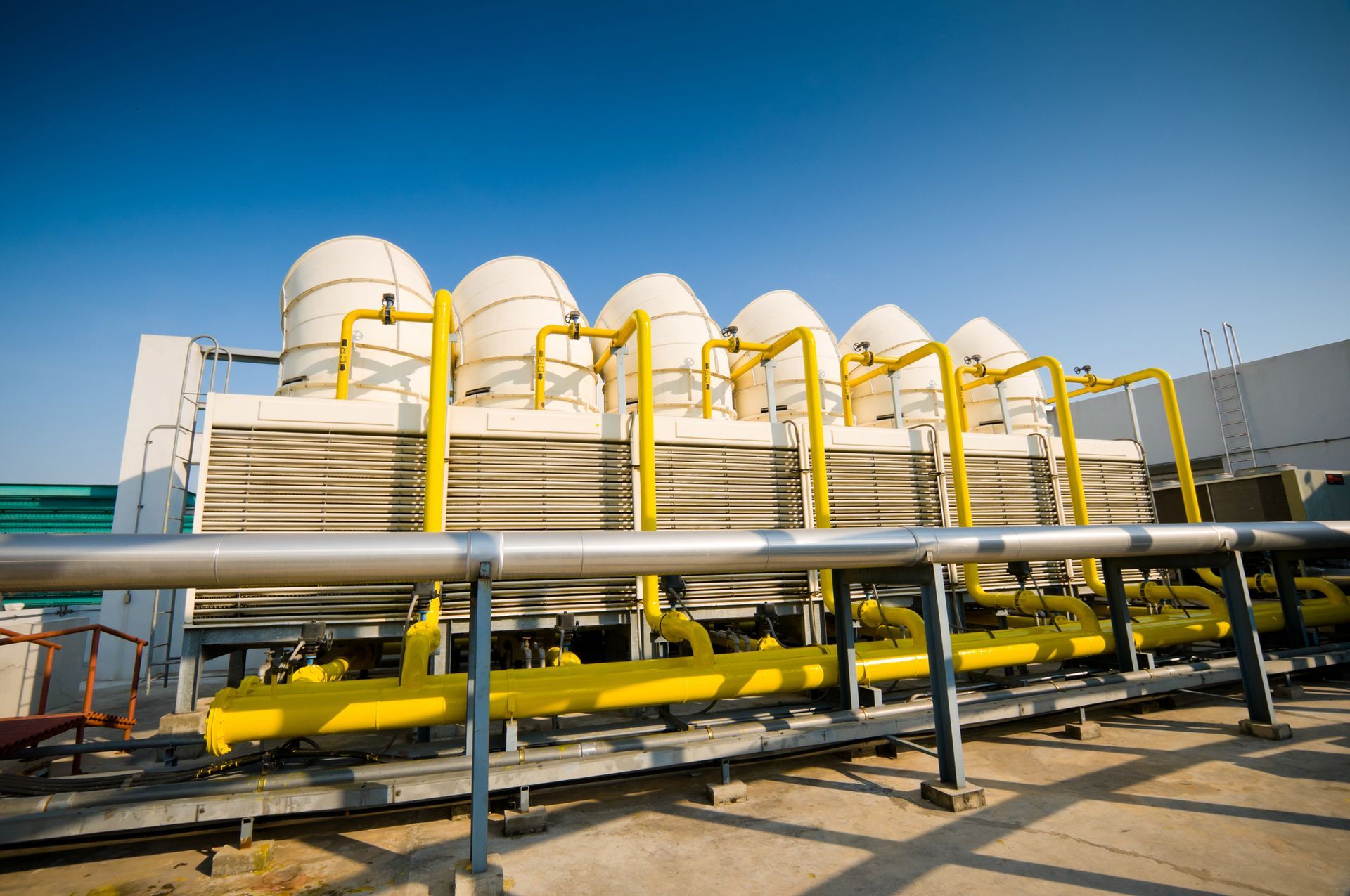 A row of cooling towers with yellow pipes surrounding them.